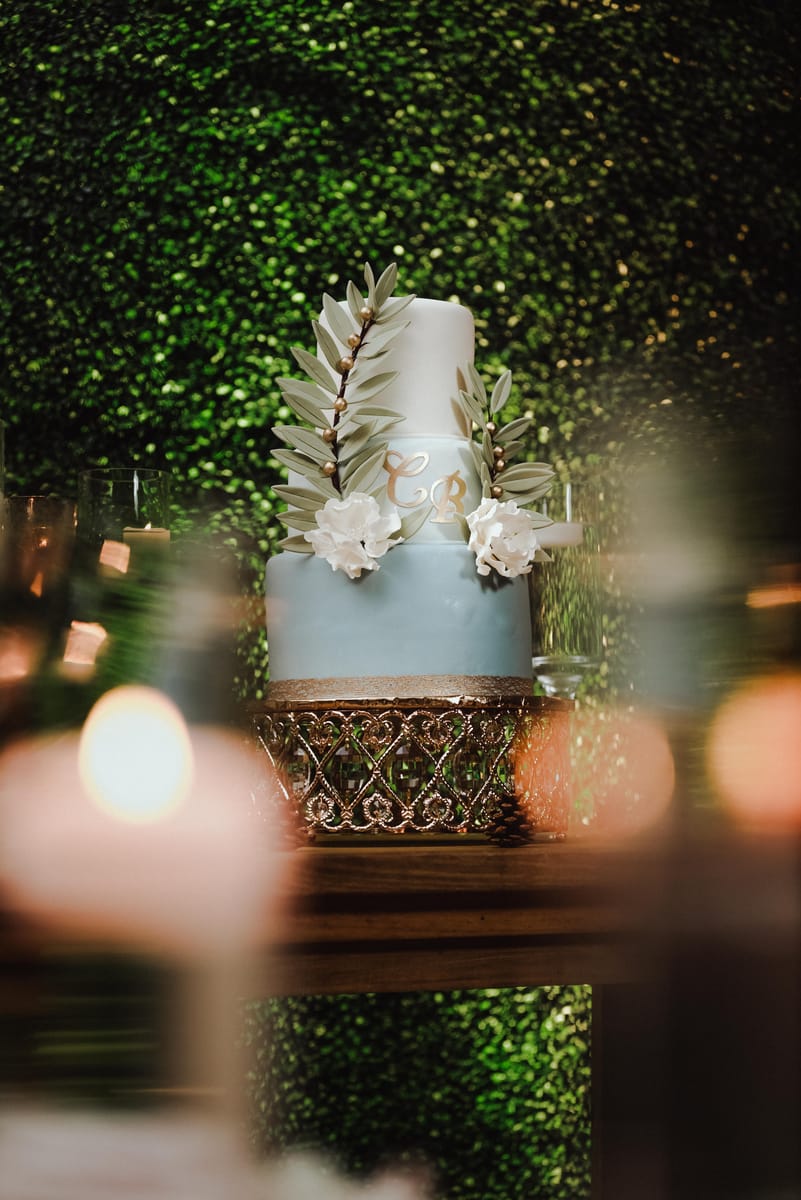 Pastel de bodas azul con hojas y flores blancas