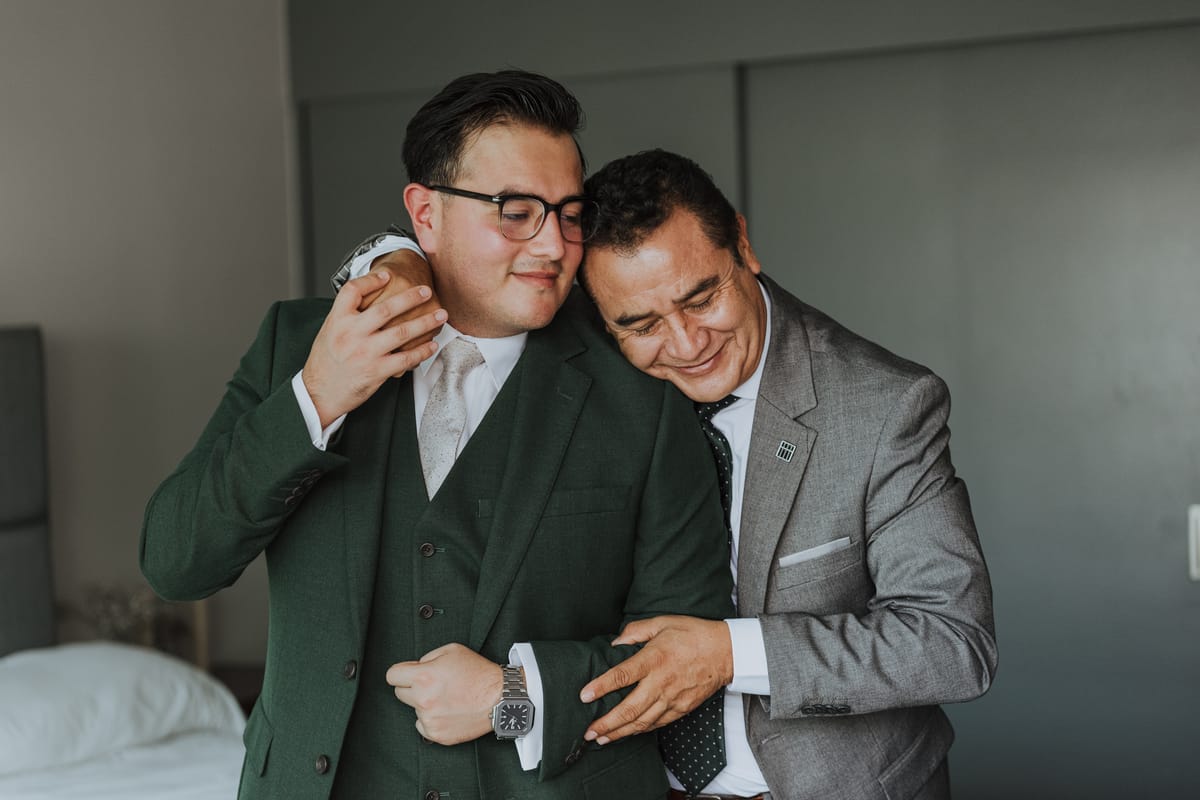 Novio y su padre se abrazan con una sonrisa