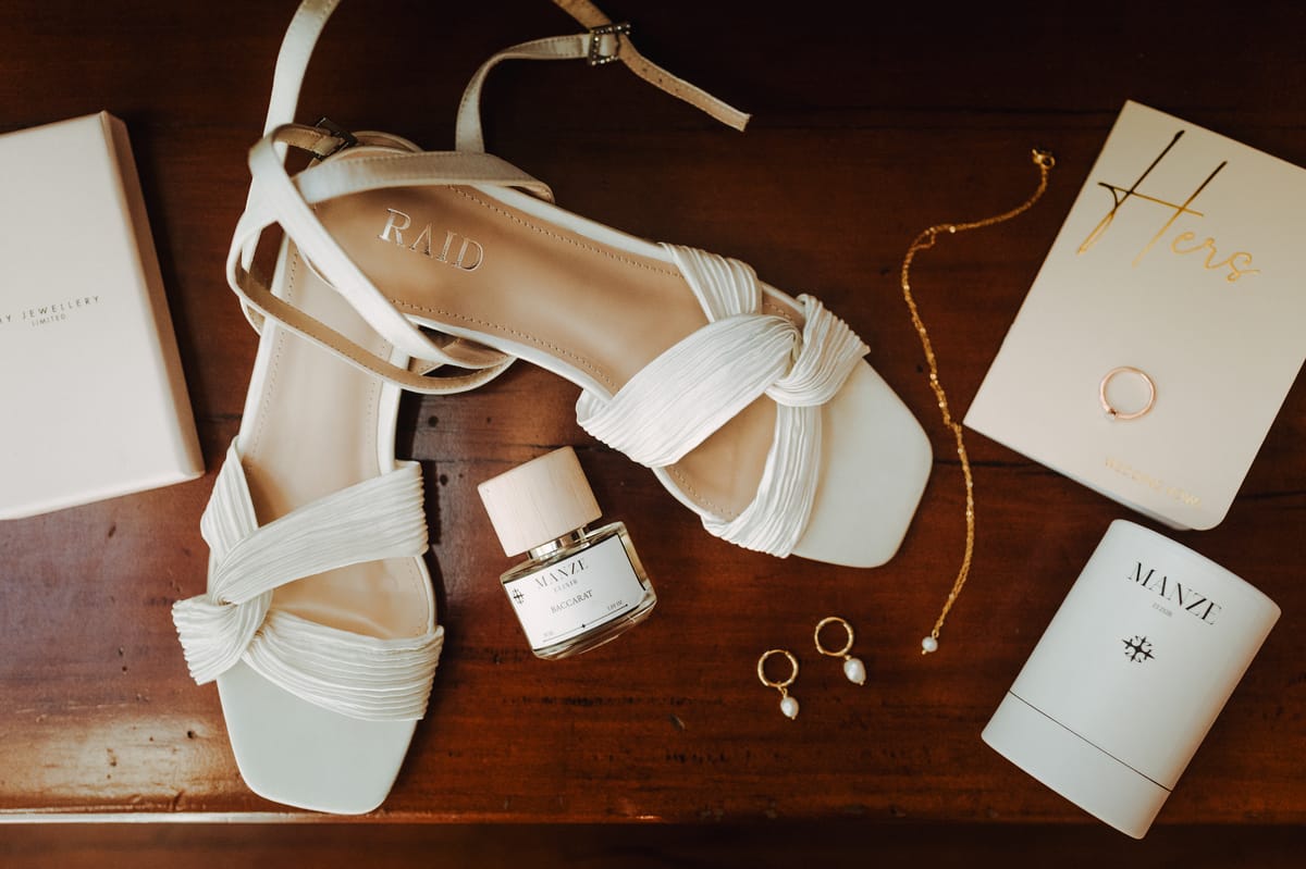 Zapatos, perfume, joyas y anillo de la novia sobre una mesa de madera