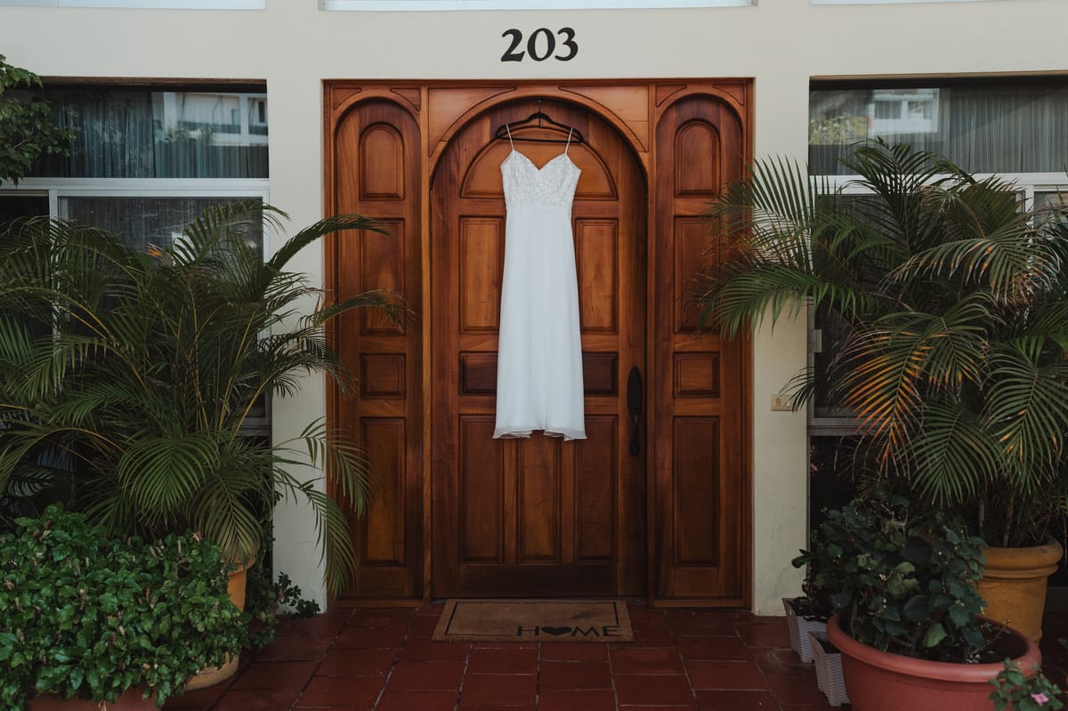 Vestido de novia colgado en una puerta de madera con arco