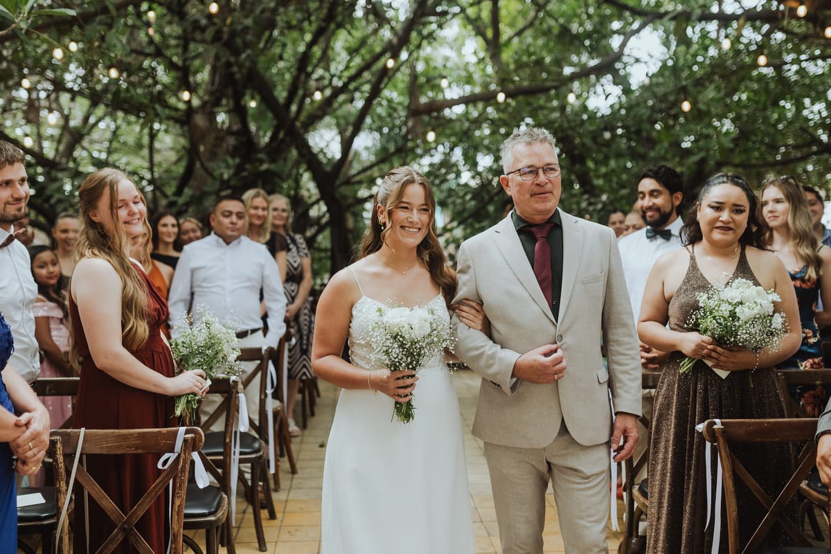 La novia camina al altar del brazo de su padre entre los invitados