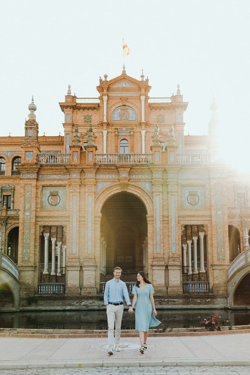 Pareja camina de la mano frente a un edificio histórico al atardecer