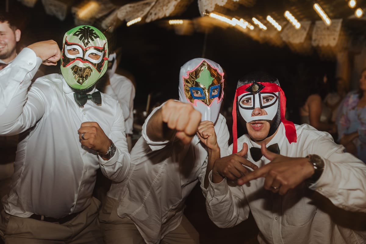 Tres invitados con máscaras de lucha libre bailan en la fiesta
