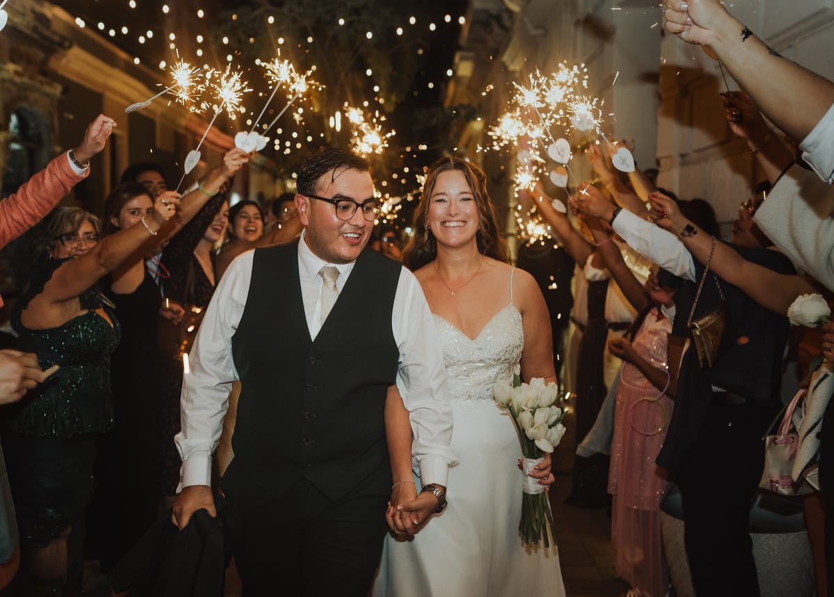 Los novios salen entre luces de bengala y sus invitados