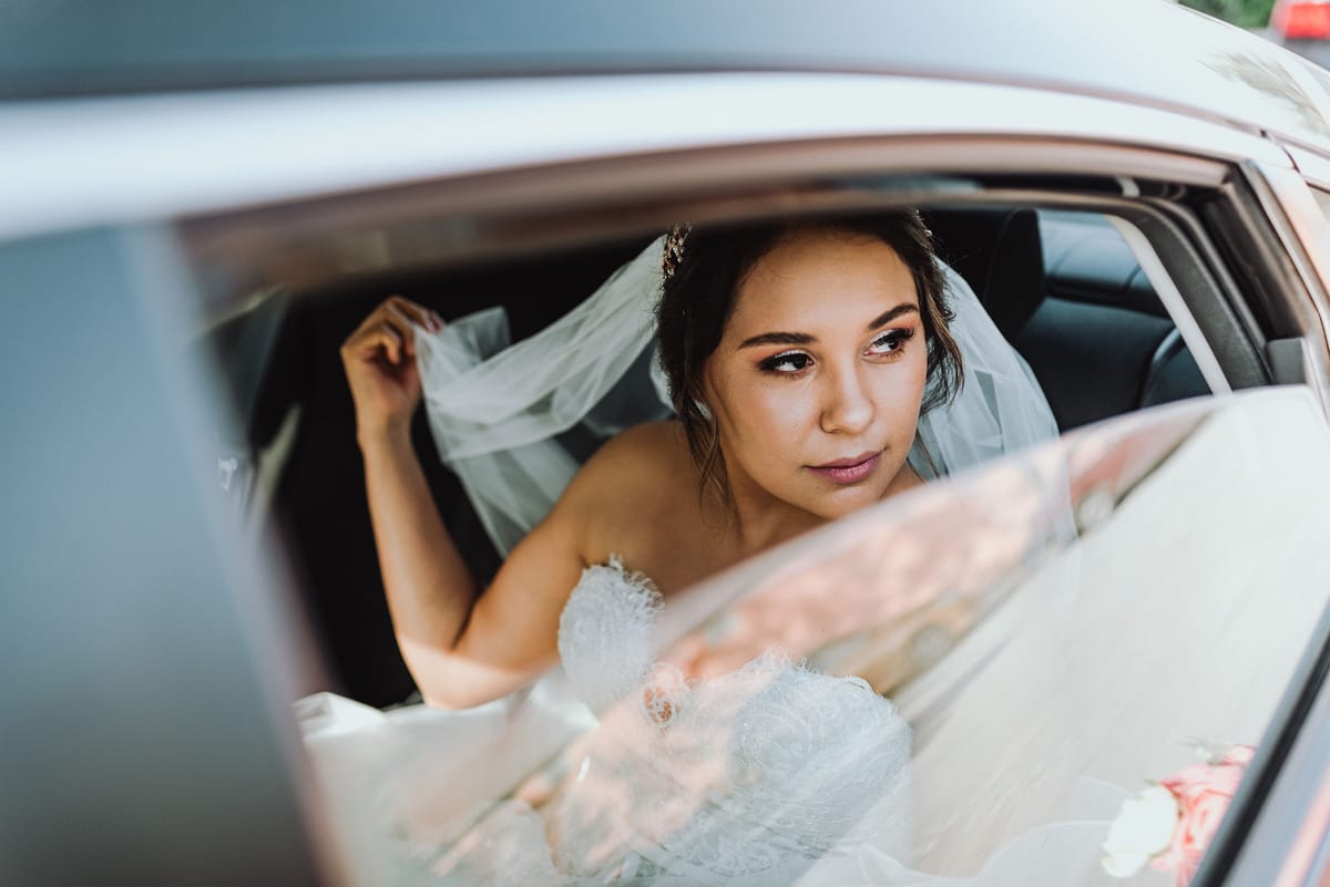 La novia con velo mira por la ventana de un auto