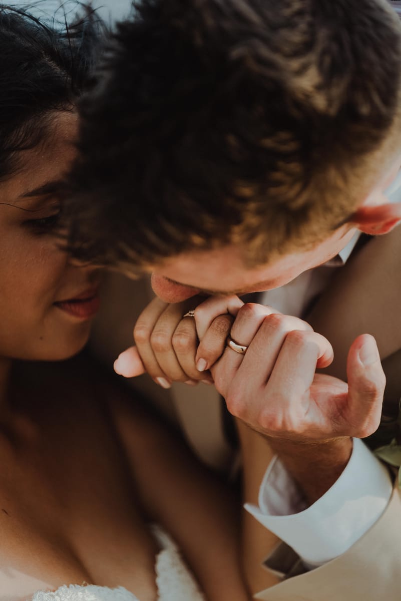 Primer plano del novio besando la mano de la novia, con las alianzas a la vista