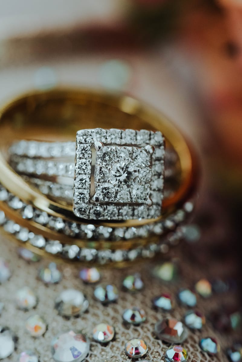 Primer plano de anillos de boda, uno de oro con diamantes, sobre una superficie de cristales